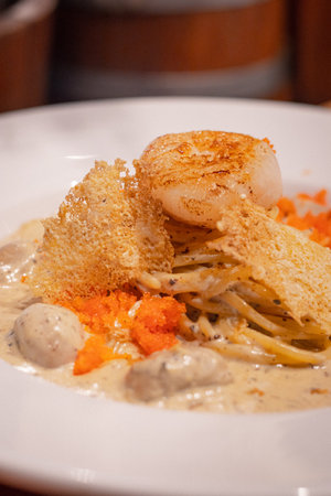 Close up, Spaghetti with scallop and truffle sauce decorated with salmon eggs on white dishの写真素材