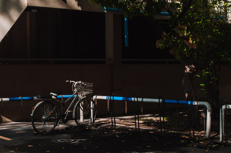 Parked bicycle next to a railing has blue and white stripes and shadows cast on the groundの写真素材
