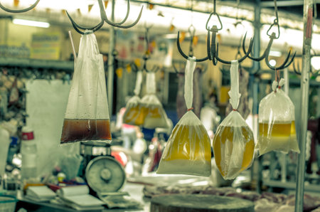 Close-up of several plastic bags filled with liquid hanging from hooks in a market, Thailandの写真素材