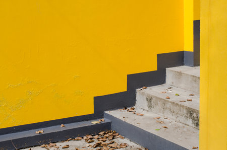 Bright yellow wall alongside a staircase with gray trim at the edge of each stepの写真素材