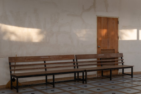 Two wooden benches positioned against a wall and a wooden door in rightsideの写真素材