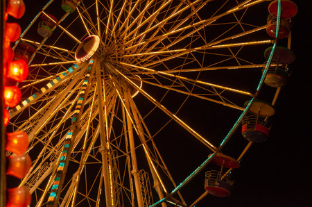 A ferris wheel viewed from below at night with bright yellow and blue lights, Chonburi, Thailandの写真素材