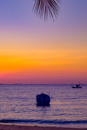 Infrered photography, a serene sunset over a body of water. In the foreground, boat floating gently on the waterの写真素材