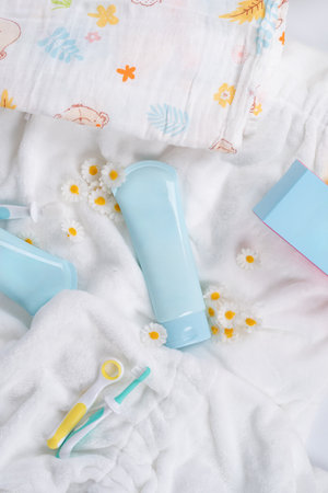 Top-view of blue tubes of lotion and blue box on a white towel with a floral pattern featuring daisiesの写真素材