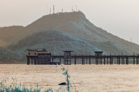 Infrared photography, a serene landscape, featuring a large body of water, a distant hill, and a wooden structure extending over the waterの写真素材