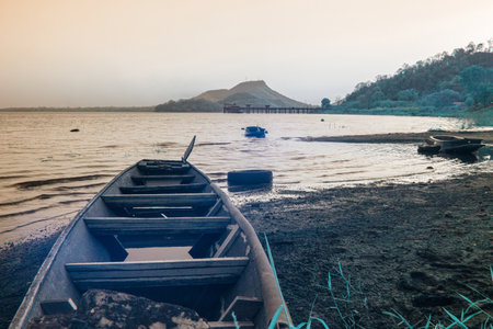 Infrared photography, a weathered wooden boat sits on the shore of a calm lakeの写真素材