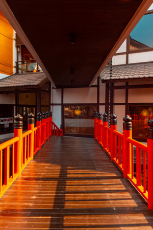 A wooden walkway with a vibrant red railing and good natural lightの写真素材