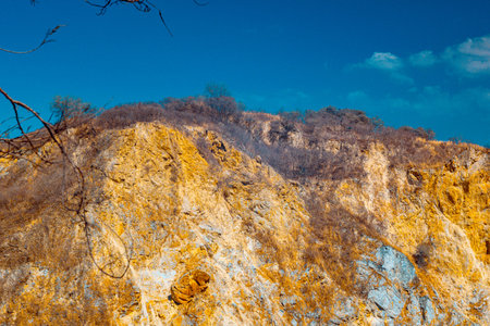 Infrared photography, a rocky cliff with a golden-brown hue, indicating a natural geological formationの写真素材