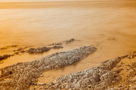 Infrared photography, a serene coastal scene with a shoreline featuring rock formations