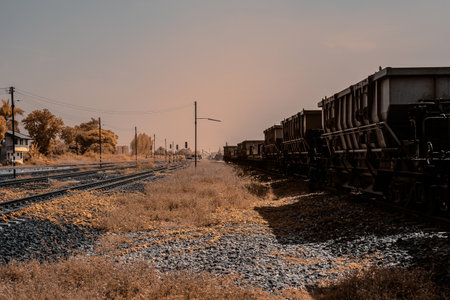 Infrared photography, a train track extending into the distance, flanked by railway cars on one side