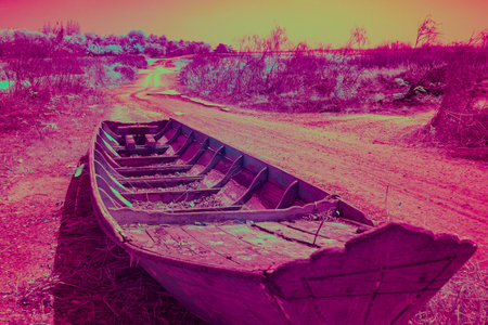Infrared photography, a wooden boat resting on a dirt path, surrounded by a barren landscapeの写真素材