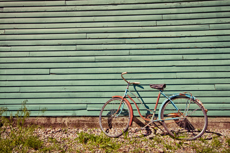 Abandoned bike leaning against a green wall.の写真素材