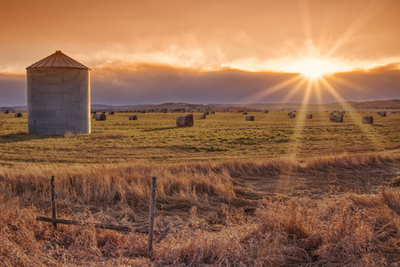 Landscape of the setting sun on the prairie with a grain elevator and sunburst.の写真素材