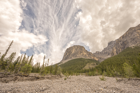 Landscape of the rocky mountains with a textured cloudy sky with a rocky bank.の写真素材