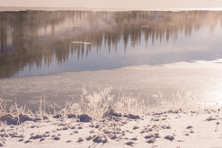 Frosty winter reflections with steam coming off water.の写真素材
