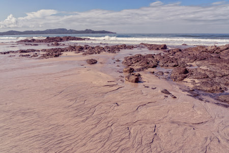 Landscape of a textured rocky beach with the ocean and hills in the distance, Playa Flamingo, Costa Ricaの写真素材