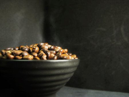 Coffee beans in a black bowl on black backgroundの写真素材