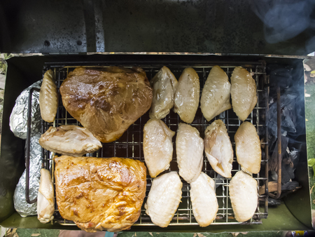 Top View Chicken Wings and Pork Shoulder Grilling on a smoking fire in a portable barbecueの写真素材
