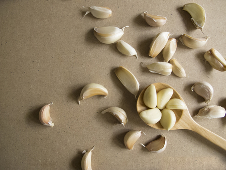 Garlic Cloves in a Wooden spoon on the MDF wooden plate board Texture Background with copy space for...