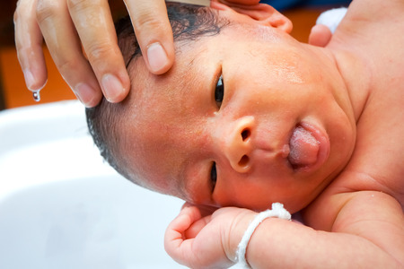 First bathing of a newborn baby boy in a  bathtub.