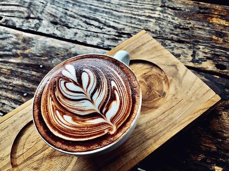 cup of coffee latte on dark wood table, beautiful latte art