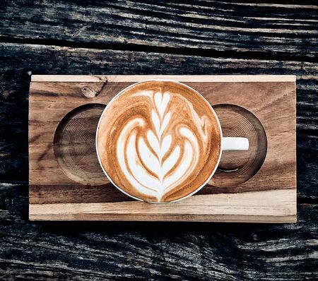 cup of coffee latte on dark wood table, beautiful latte art
