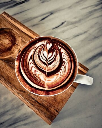 cup of coffee latte on dark wood table, beautiful latte artの写真素材