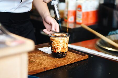 a cup of brown sugar flavored tapioca pearl bubble milk tea in night market of Taiwan background,