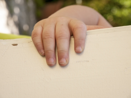 a young hand of a toddler on a wooden beamの写真素材