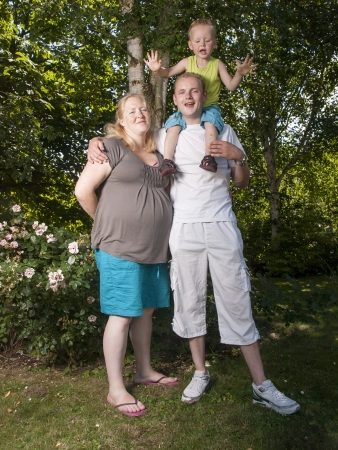 happy family with pregnant mother with toddler in a gardenの写真素材