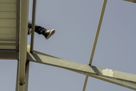 Construction worker lay down on the roofing sheet on Light steel Truss and Frame construction.