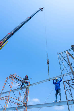 Crane and Worker conect the steel beam with the srell pole by gas welding.のeditorial素材