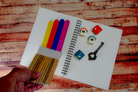 Wooden paint stick and paint brush with Home toy  and accessories on white paper.の写真素材