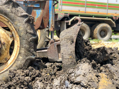 The tractor is adjusting the soil. Dumper in the background. The tractor is  pushing  the soil.の写真素材