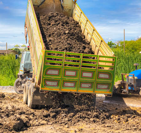 A Dump truck big enough to haul that lot of soil , dumper pouring the soil.The thactor is ready to adjust the soil.の写真素材