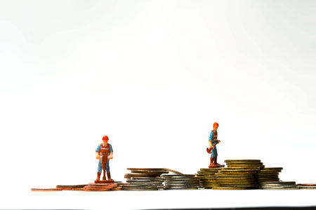 Two Constructions models working hard on coins. Contractor isolated on white background. Working hard save money concept ideas.の写真素材