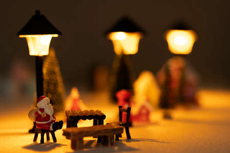 Santa Claus sits back and relax in front of mailbox with red and yellow hut with snow on the roof.の写真素材