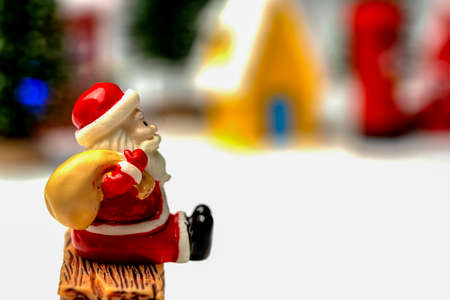 Santa Claus sits back and relax in front of mailbox with red and yellow hut with snow on the roof.の写真素材