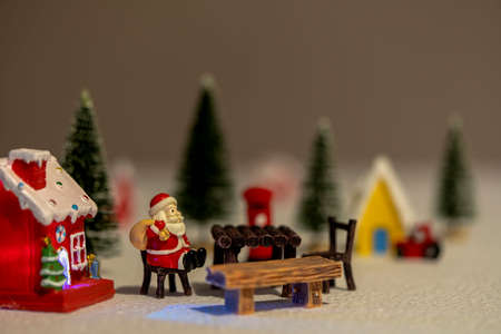 Santa Claus sits back and relax in front of mailbox with red and yellow hut with snow on the roof.の写真素材