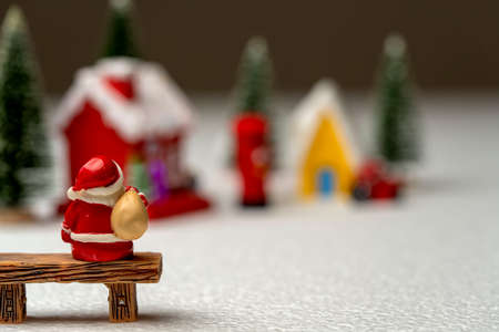 Santa Claus carrying a bag sitting on a bench.