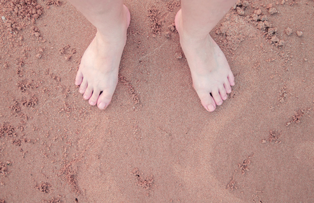 soft focus of woman foot stand on the sand texture.Art photo. Vintage tone.の写真素材