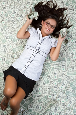 Smiling woman laying in moneyの写真素材