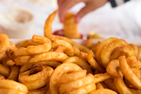 Curly fries with hand dipping in ketchupの写真素材