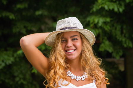 Smiling girl with white necklace and straw hatの写真素材