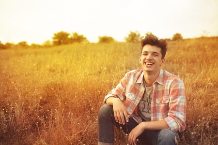 Casual smiling young man sitting outdoor in autumnの写真素材