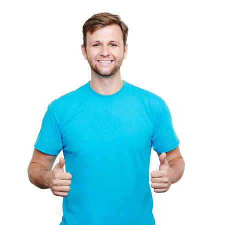 Smiling young male wearing blue t-shirt giving thumbs up against a white backgroundの写真素材