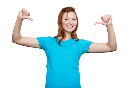 t-shirt design concept. happy young woman in blank blue t-shirt smiling and pointing at herself, isolated on whiteの写真素材