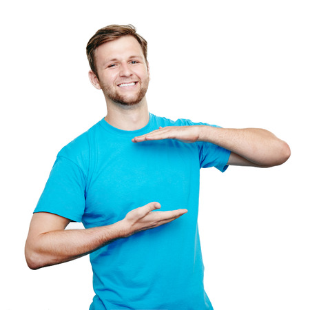 Happy young man showing space on blank blue t-shirt. Product placement and promotion conceptの写真素材