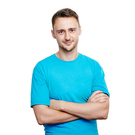 Handsome young man with arms crossed wearing blue t-shirt, smiling while standing isolated on whiteの写真素材
