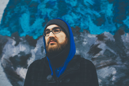 Portrait of bearded young man wearing winter clothes and eyeglasses outdoors.